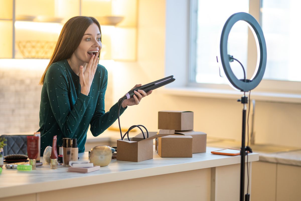 Mulher gravando vídeo: colocar produtos no Instagram Mulher gravando vídeo de divulgação de produtos com smartphone e ring light