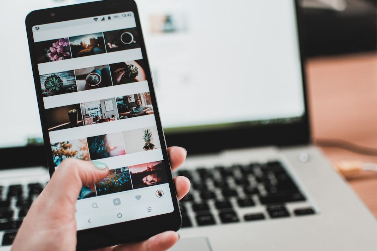 Mulher segura smartphone: colocar produtos no Instagram Smartphone segurado por mão feminina enquanto exibe vitrine de produtos virtual