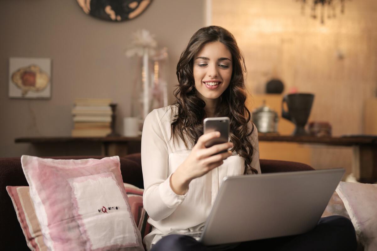 mulher usando laptop e celular: facebook ads e google ads mulher sentada, usando o laptop e o celular ao mesmo tempo