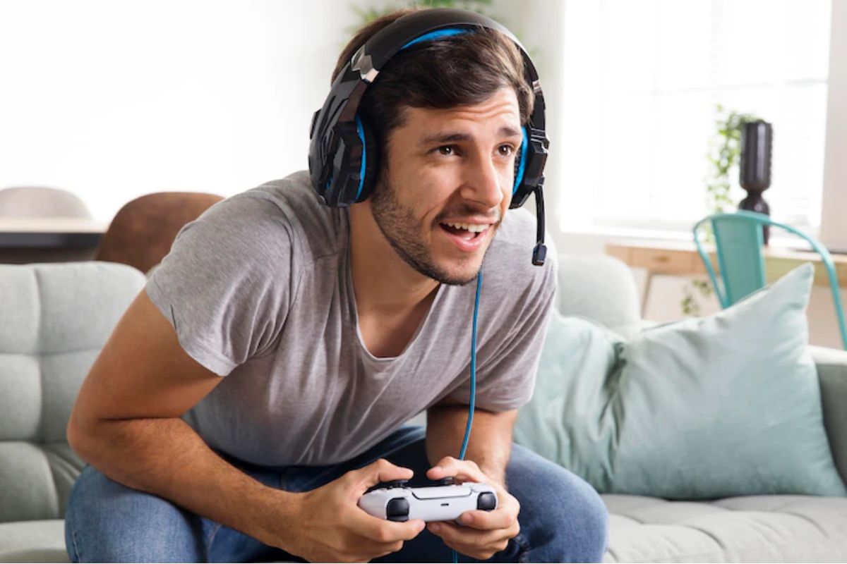 pessoa jogando videogame: game as a service homem empolgado com um controle de videogame nas mãos e fone de ouvido