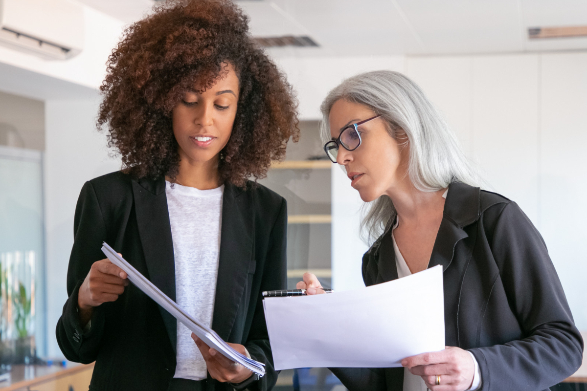 Mulheres em escritório: mapa conceitual Mulheres conversando em escritório enquanto seguram folhas com relatórios