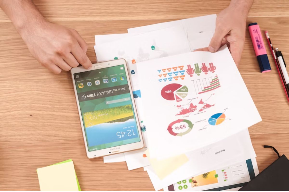 análise de gráficos: marketing de produto homem analisando folhas com gráfico e mexendo no celular