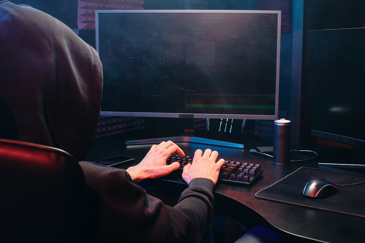 pessoa digitando: phishing homem de capuz todo de preto digitando em um teclado de computador