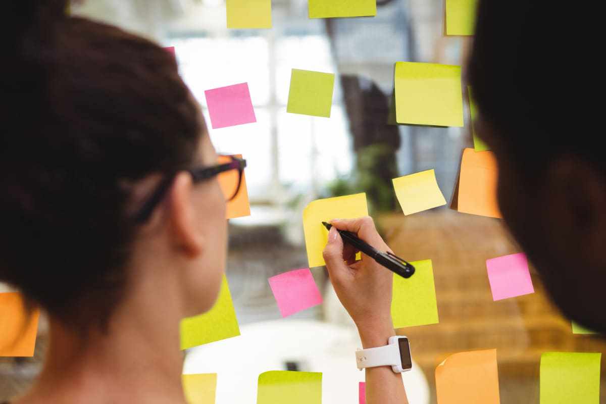 Post-its: planejamento estratégico Pessoas usando post-its em janela de vidro para planejamento estratégico