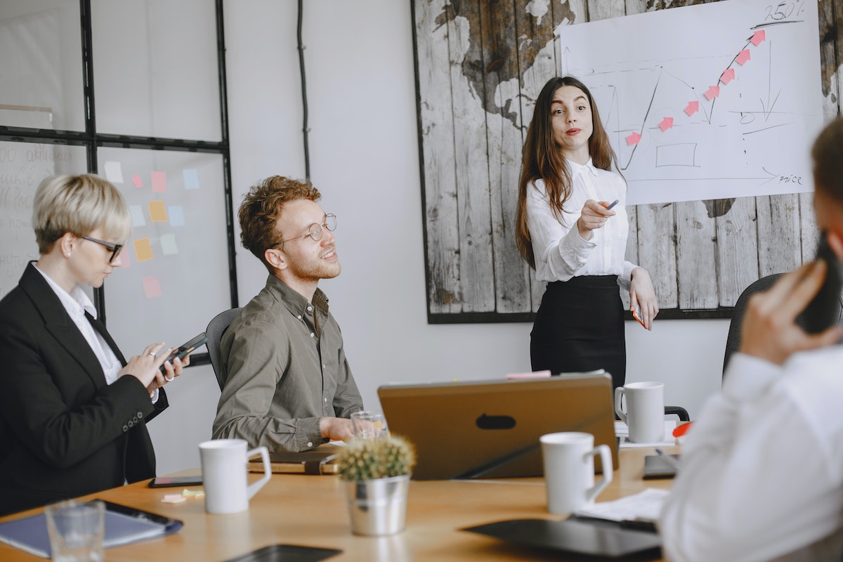 O que faz um profissional de marketing? Conheça os principais cargos profissionais reunidos trabalhando em uma sala de reuniões