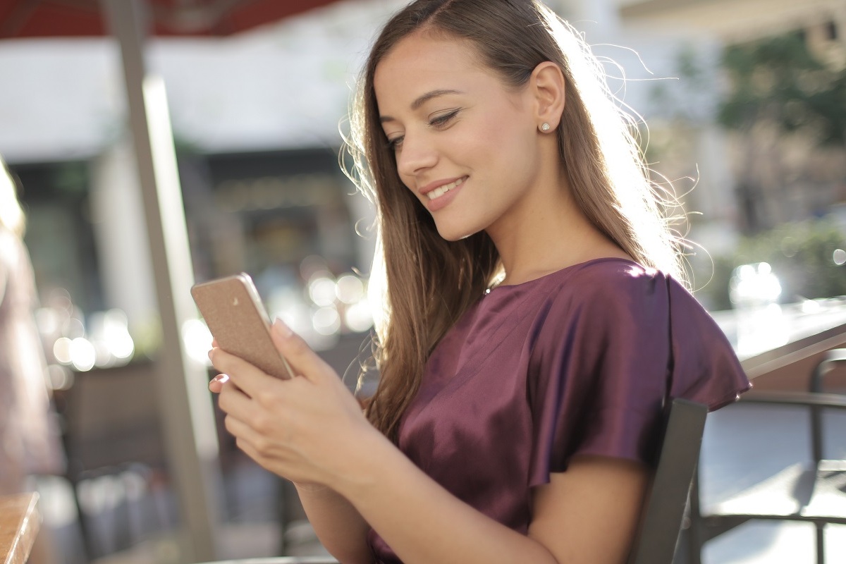 jovem usando o celular: sac 2.0 mulher jovem sorrindo enquanto mexe em seu celular