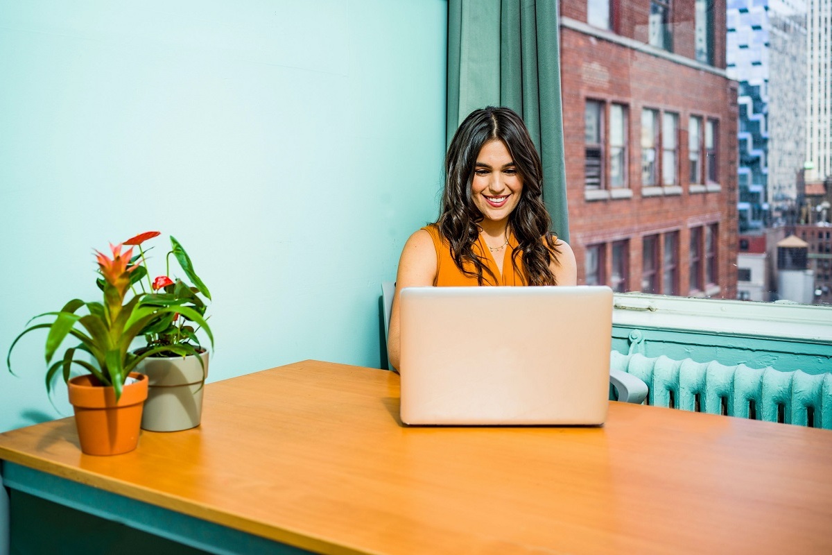 mulher jovem sorrindo enquanto digita em seu notebook