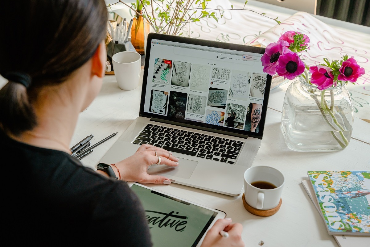 mulher trabalhando: alt-text mulher sentada, trabalhando em seu laptop e do lado dela, há uma xícara de café