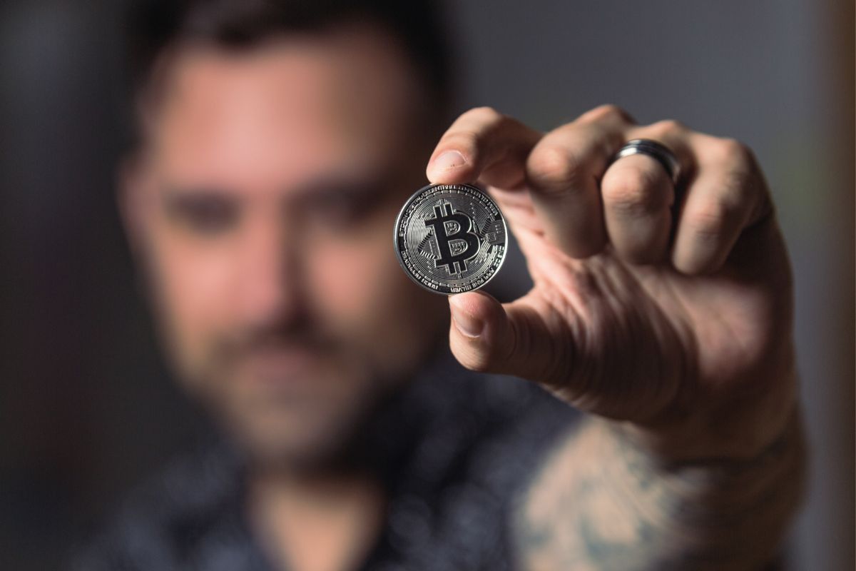homem segurando um bitcoin