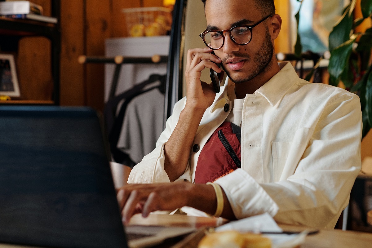 homem falando no celular: estratégia de blog homem falando no celular enquanto usa o laptop