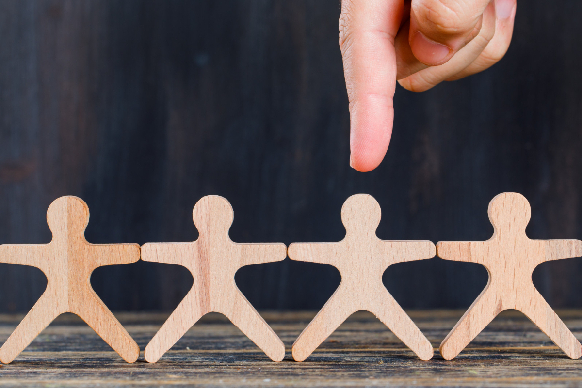 vários bonecos de madeira, unidos pelas mãos