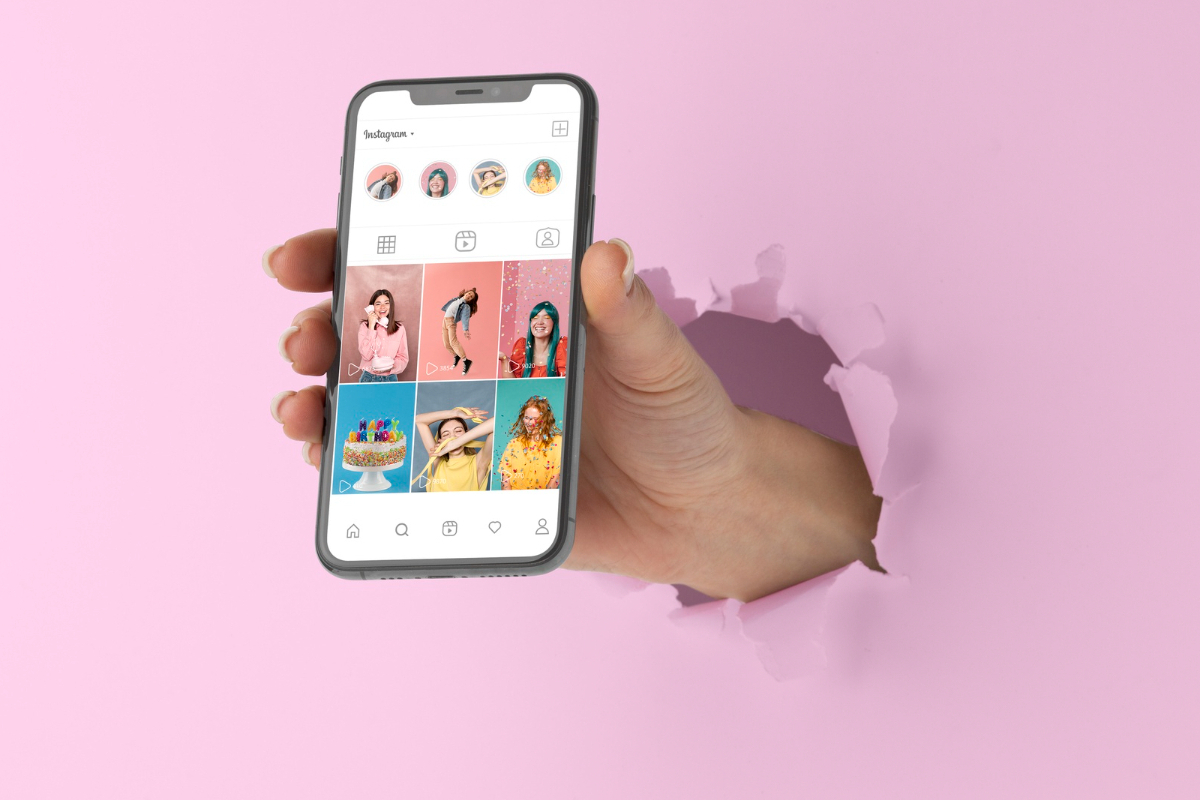 mão segurando um celular: marketing pessoal nas redes sociais mão saindo de uma parede rosa, segurando um celular