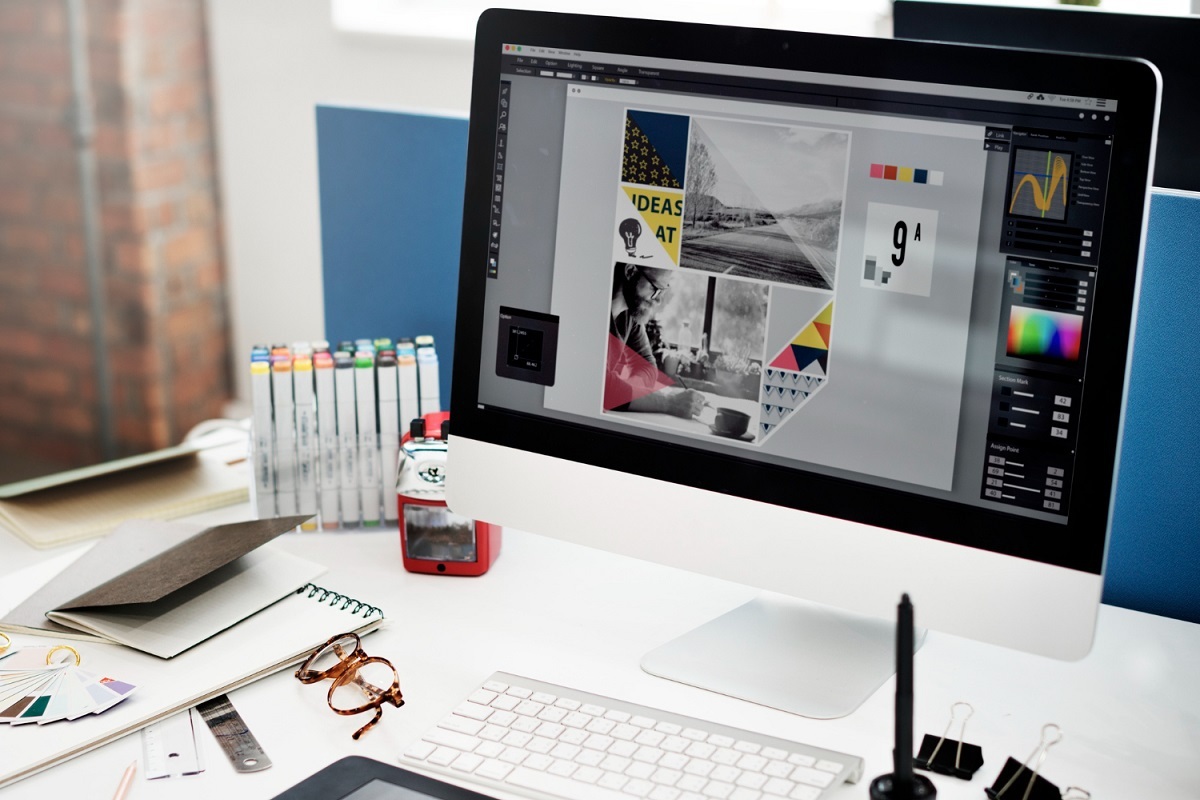 mesa com computador mostrando um programa de edição de fotos
