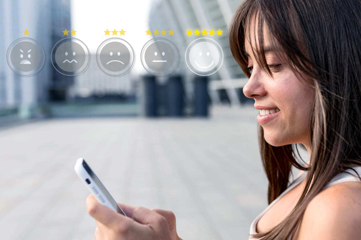 mulher usando o celular: pesquisa de mercado mulher usando o celular e, na imagem, há ilustrações de emojis de satisfação