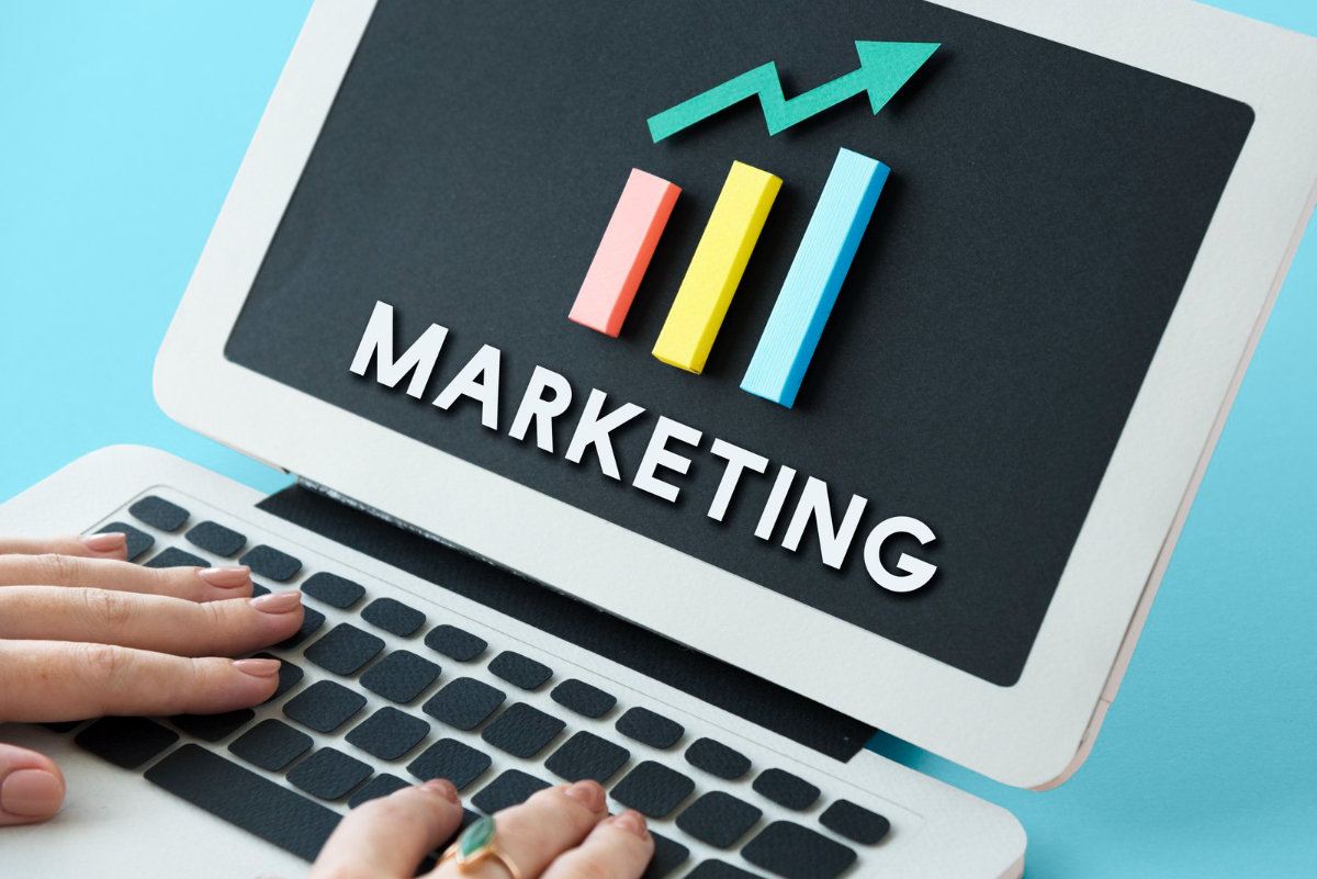 Notebook branco: Philip Kotler marketing escrito na tela de um notebook e mãos femininas sobre teclado