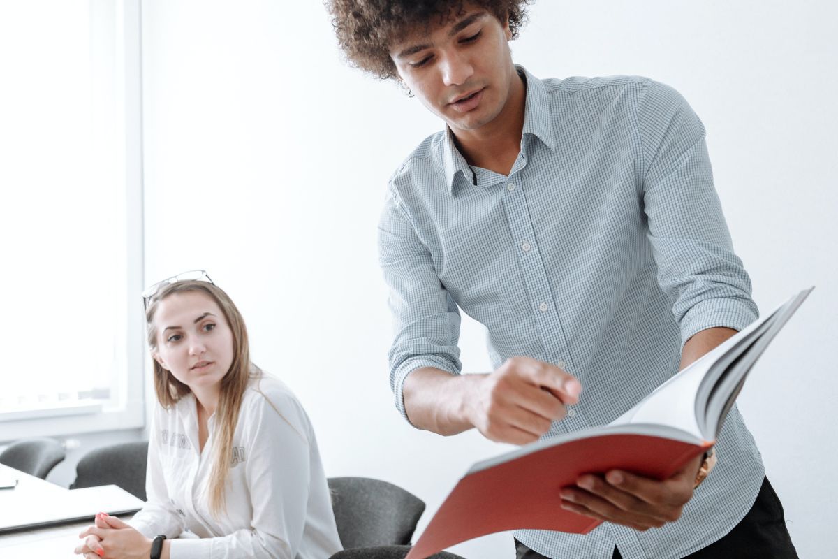 pessoas no trabalho: rapport homem mostrando algo em seu caderno para sua colega de trabalho