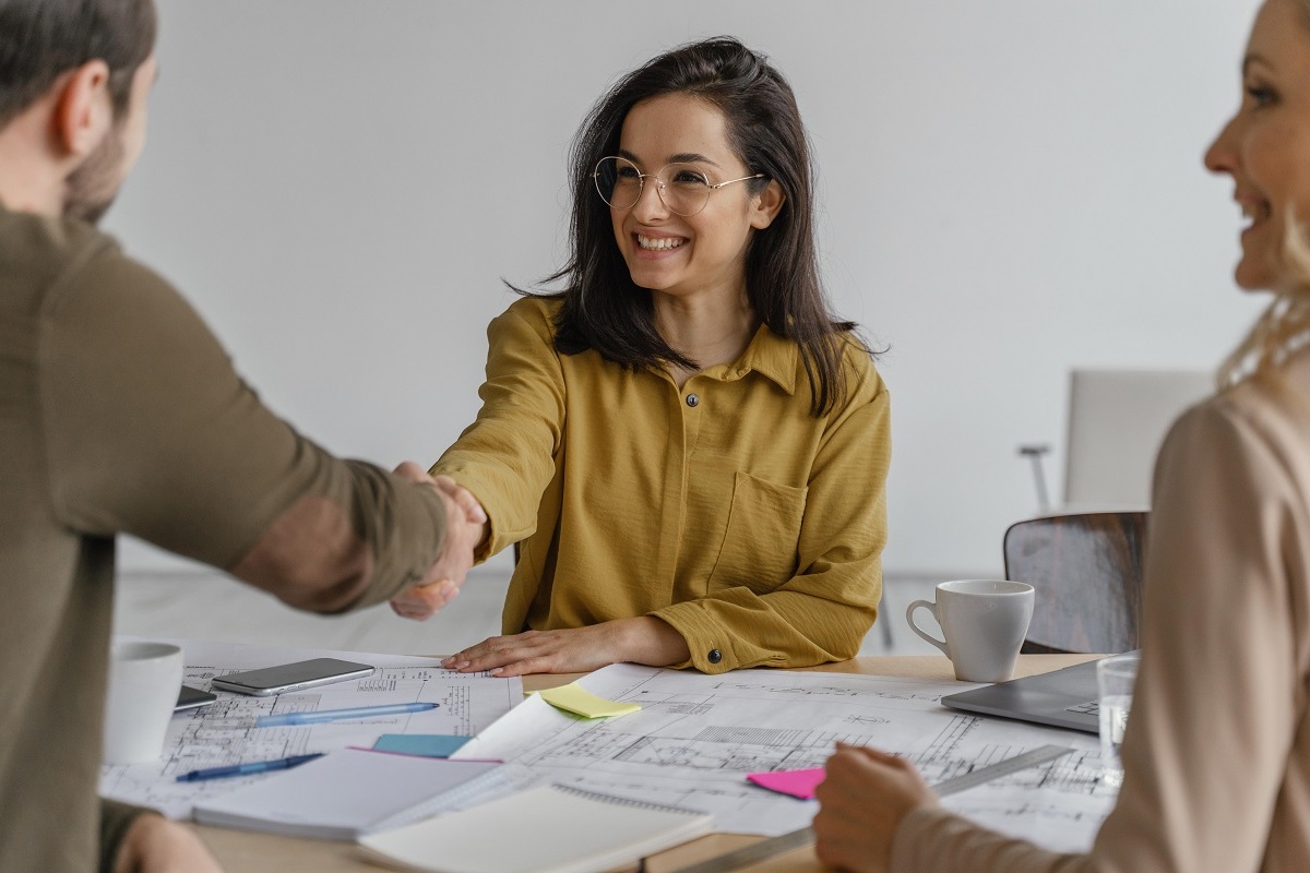 mulher jovem sorrindo e apertando a mão de um homem