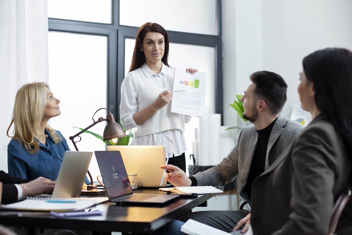 pessoas em reunião: topo de funil mulher de pé mostrando um relatório para seus companheiros de trabalho