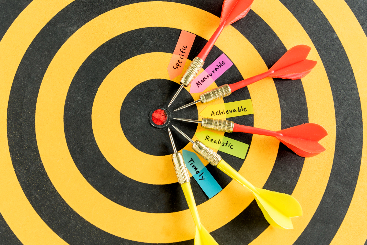 alvo amarelo e preto, cheio de pinos com nome escritos em papéis e presos a eles