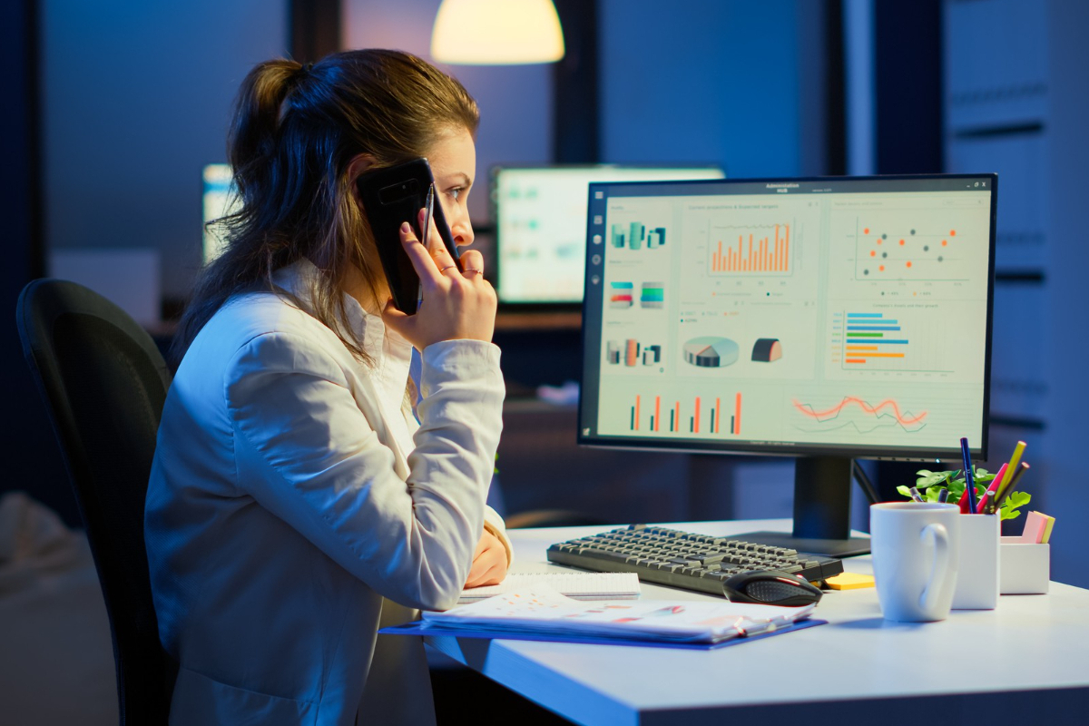 mulher sentada, trabalhando em seu computador em um escritório e falando ao telefone