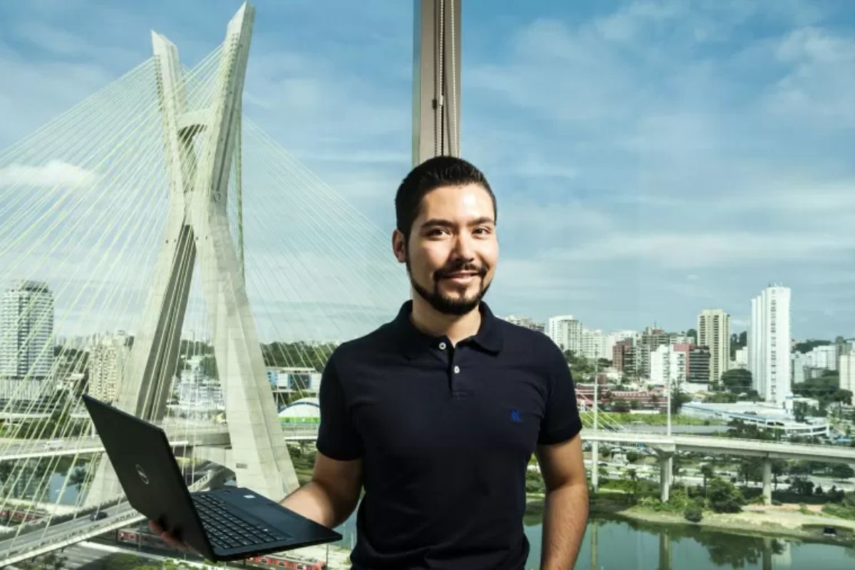 Montagem: analista de canais Homem com notebook na mão na frente da ponte Octávio Frias de Oliveira em São Paulo em montagem