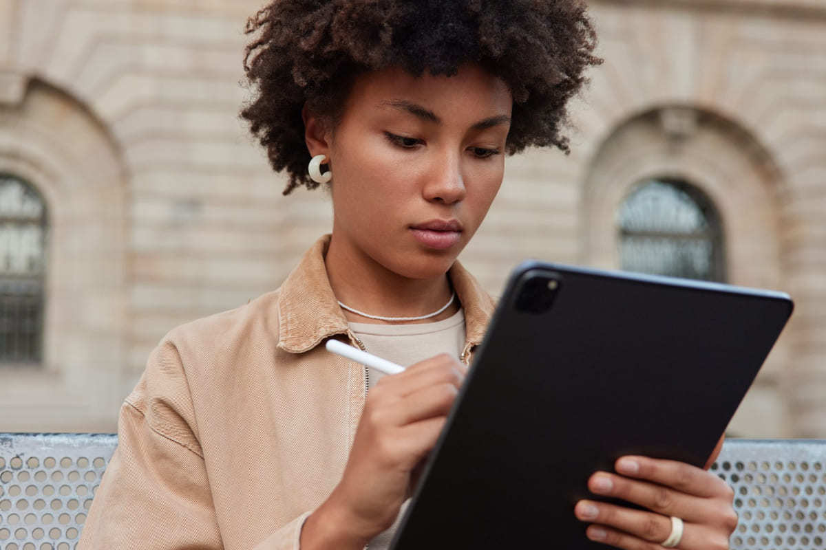 Tablet: Aplicativos de fotos Mulher em calçada diante de prédio antigo usando tablet com caneta touch na mão