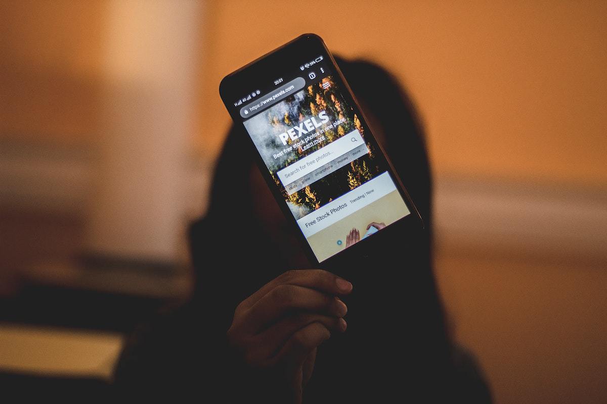 Navegador: app store optimization Mulher com mão erguida mostrando tela de celular aberto no site Pexels