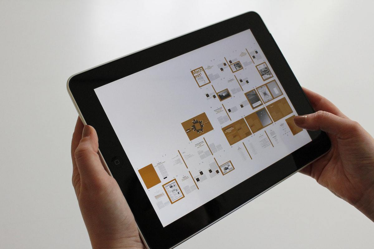 Mãos femininas segurando tablet  enquanto analisa imagens de suposto projeto