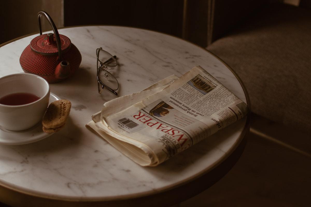 jornal em cima de uma mesa junto com uma xícara de café