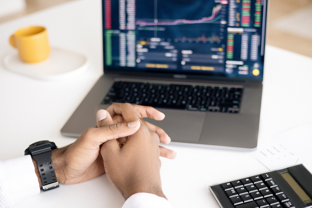 Gráficos: crowdfunding Homem com relógio preto no pulso esquerdo com mãos diante de notebook que exibe gráficos com os dedos entrelaçados