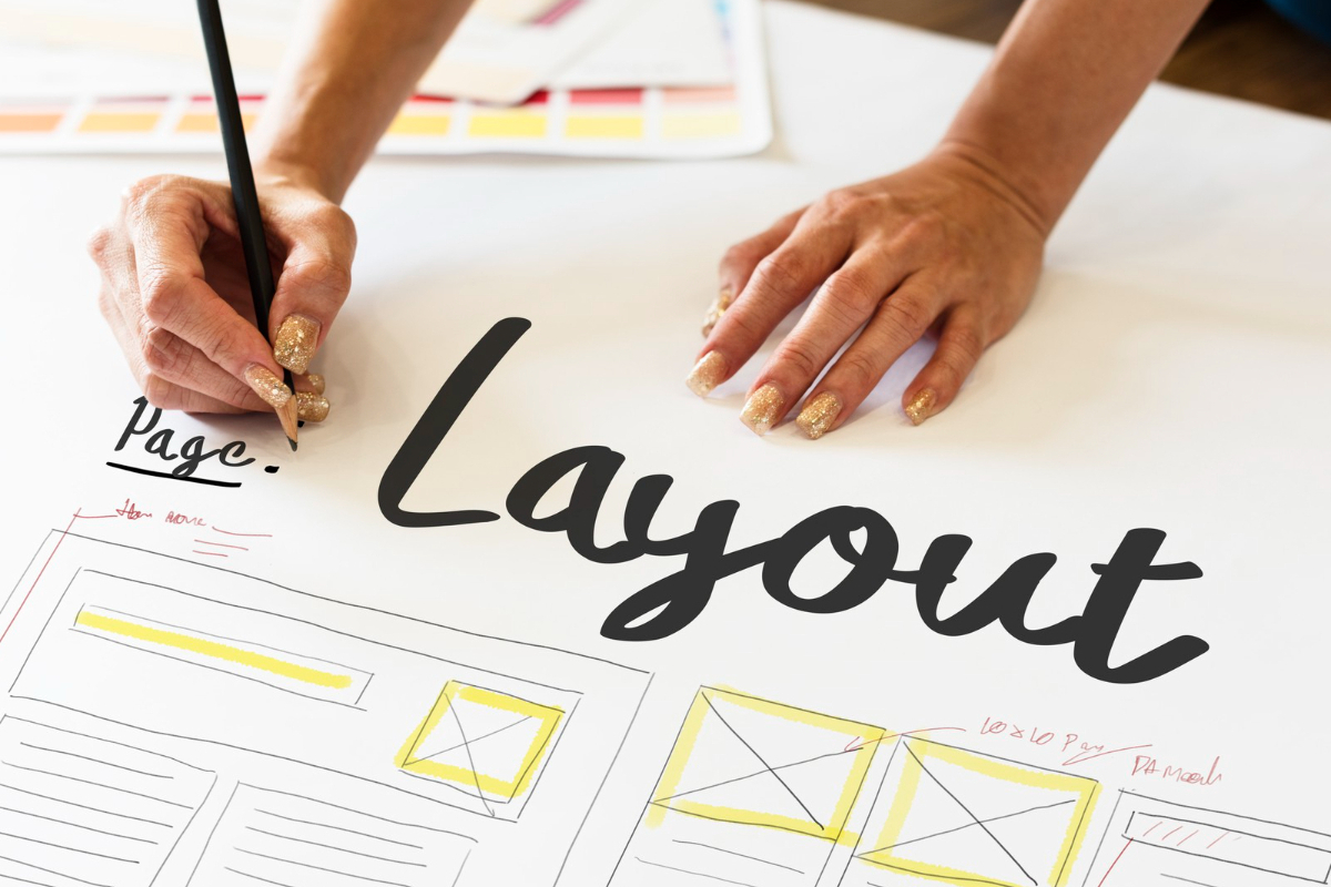 Mãos femininas segurando lápis e desenhando em grande folha de papel que representa um layout de landing page