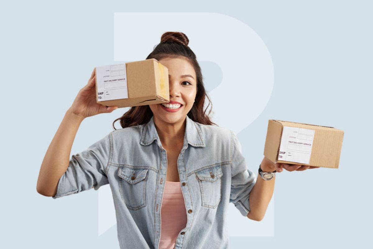 Mulher sorridente: fidelização do cliente em e-commerce Mulher sorridente segurando caixas de compras com uma delas cobrindo parte do rosto