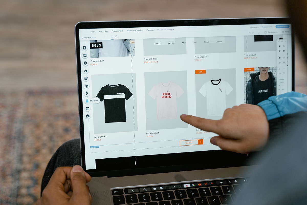 Duas pessoas usando notebook em colo escolhendo camisetas em um e-commerce