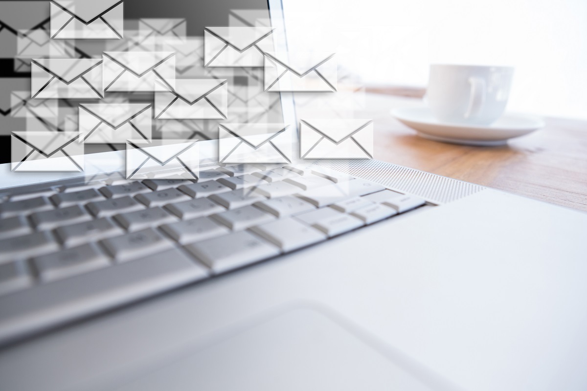 Notebook: limpar base de e-mails Notebook cinza sobre mesa de madeira e ao lado de xícara com símbolos web de cartas espalhados na imagem