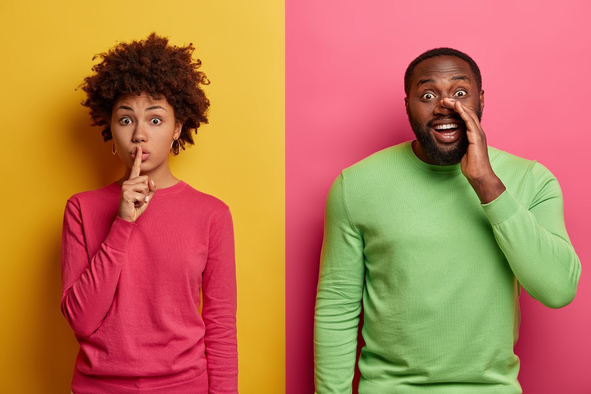 Pessoas gesticulando: Marketing boca-a-boca Homem e mulher diante de parede colorida, enquanto ela faz sinal de silêncio e ele põe mão à boca como se gritasse algo