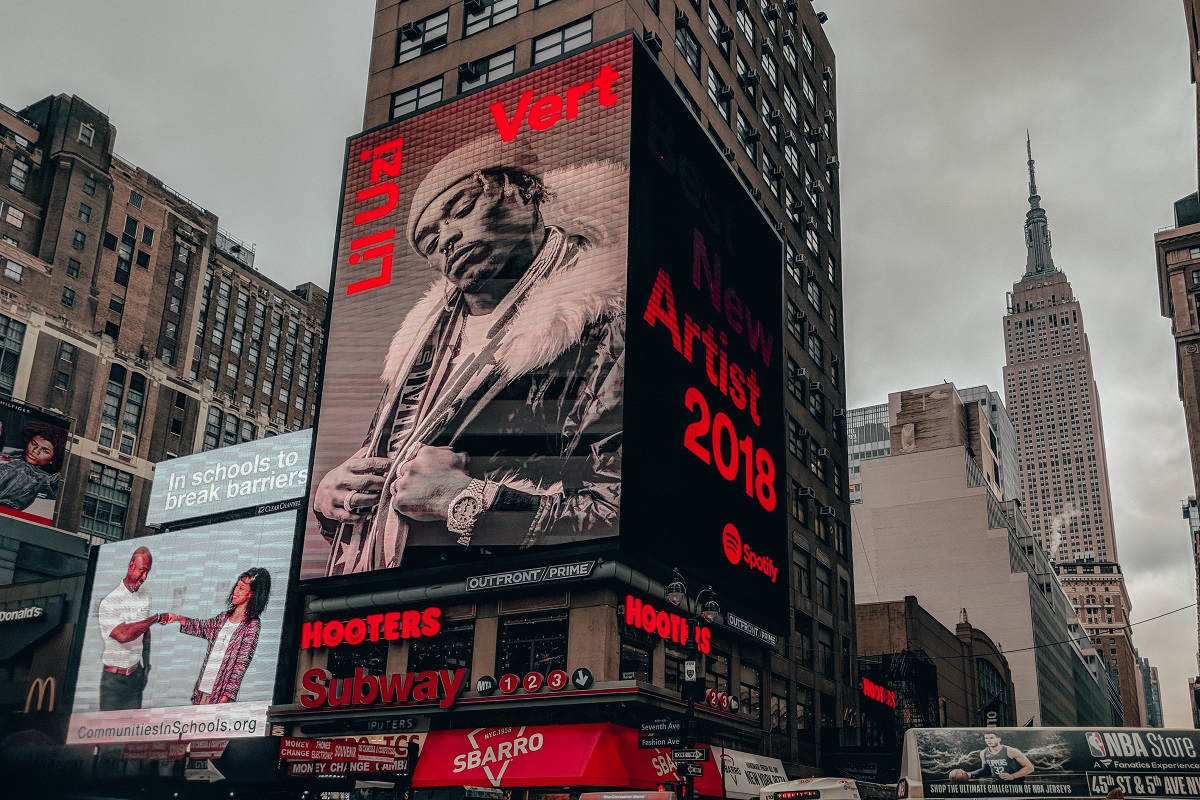 Propagandas em telões e painéis gigantes posicionados em prédios altos em avenida de grande cidade