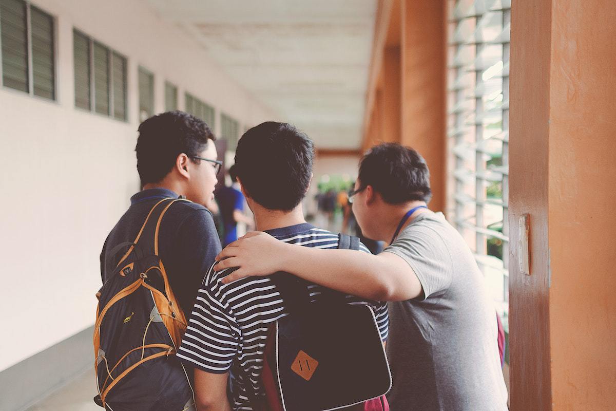 Três homens conversando em corredor de instituição