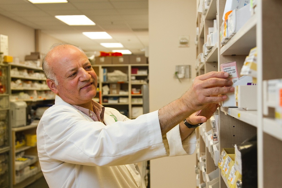 Remédios: Marketing farmacêutico Senhor de jaleco de farmacêutico diante de prateleiras procurando algum remédio