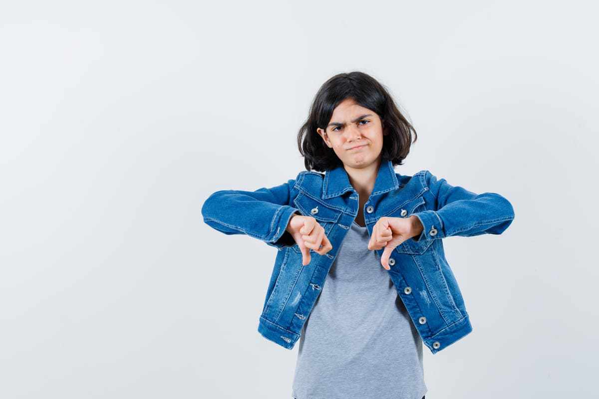 Menina com jaqueta jeans e fazendo sinal de negativo com dois braços