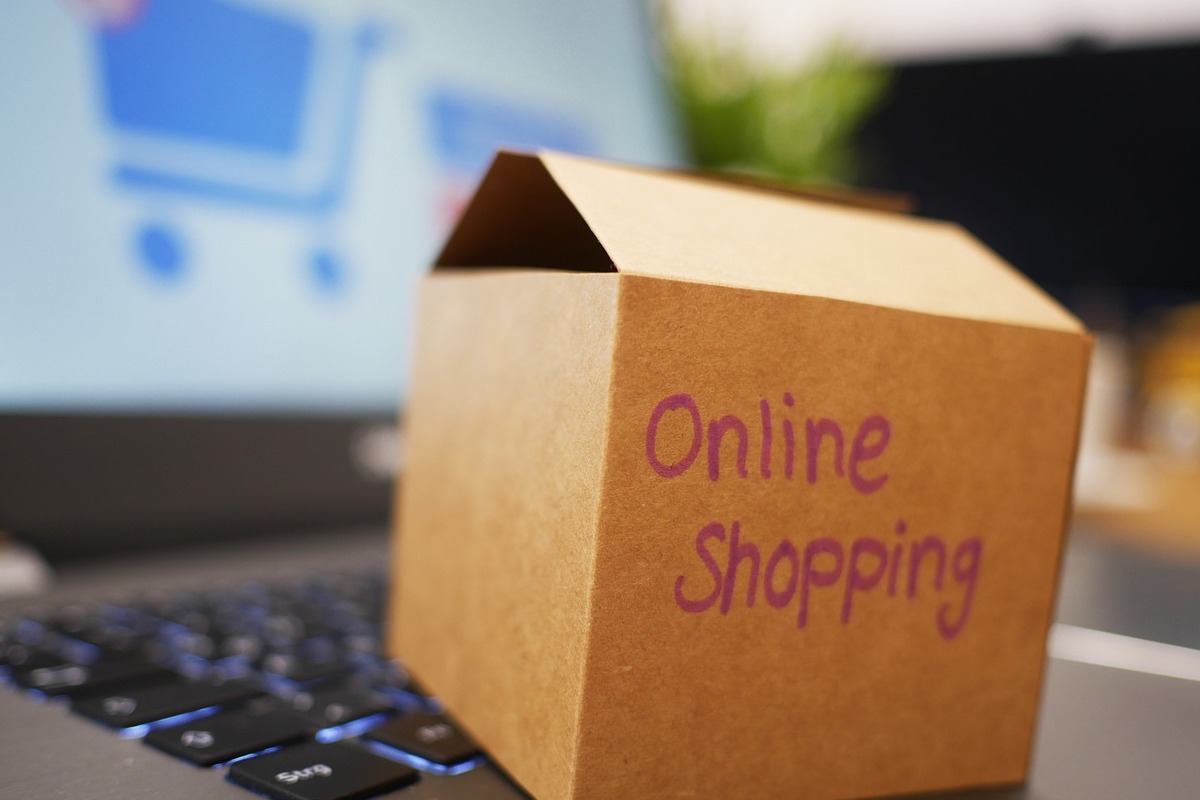 Notebook em desfoco na imagem com caixa pequena em cima do teclado com frase escrita Online Shopping