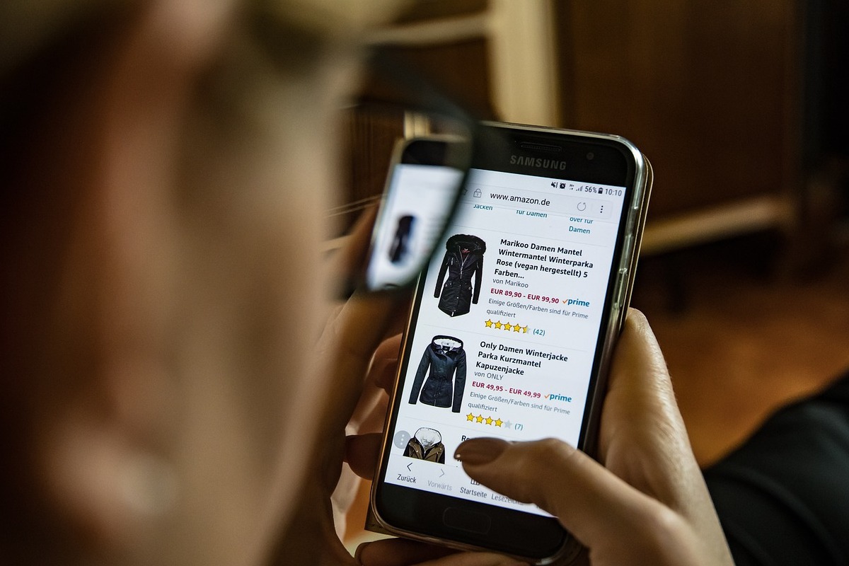 Pessoa segurando smartphone e olhando dados em site de loja de roupas