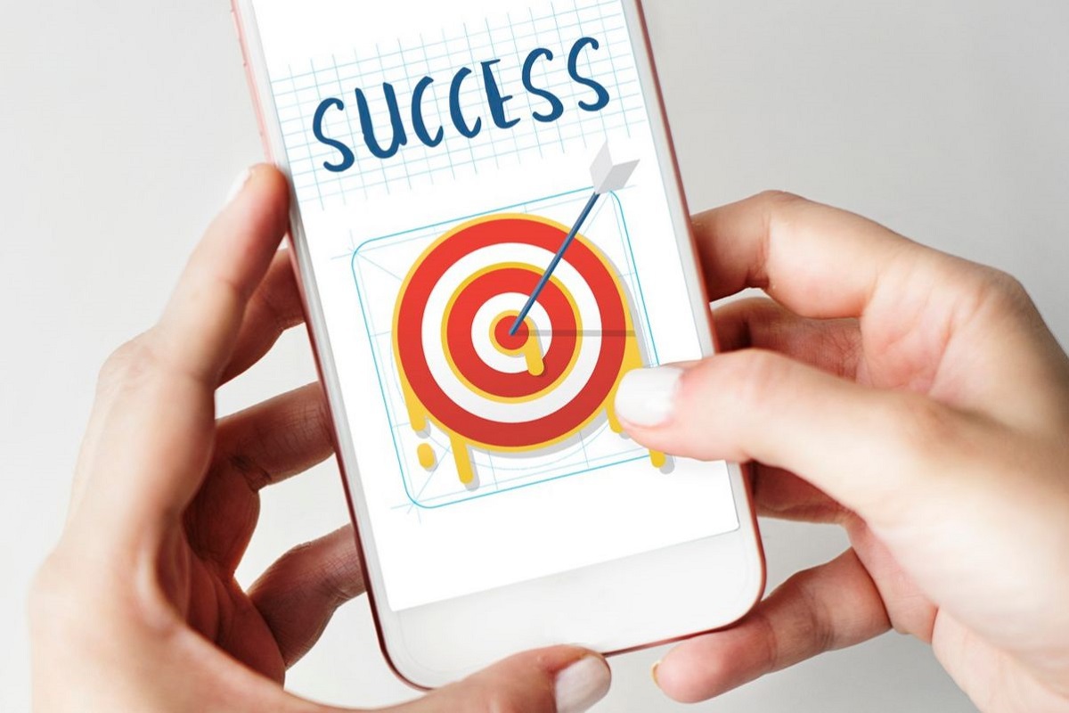 Celular: Processos de marketing Mãos de mulher segurando celular com montagem na tela com flecha acertando alvo e nome sucesso em inglês