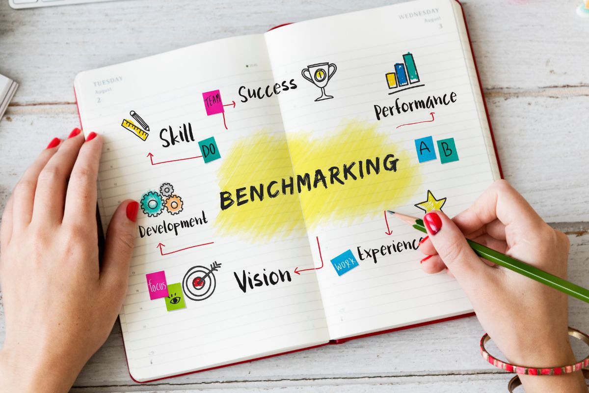 Mãos femininas: reconhecimento de marca Mãos de mulher segurando lápis de cor em livro aberto com nome Benchmarketing e outros dados