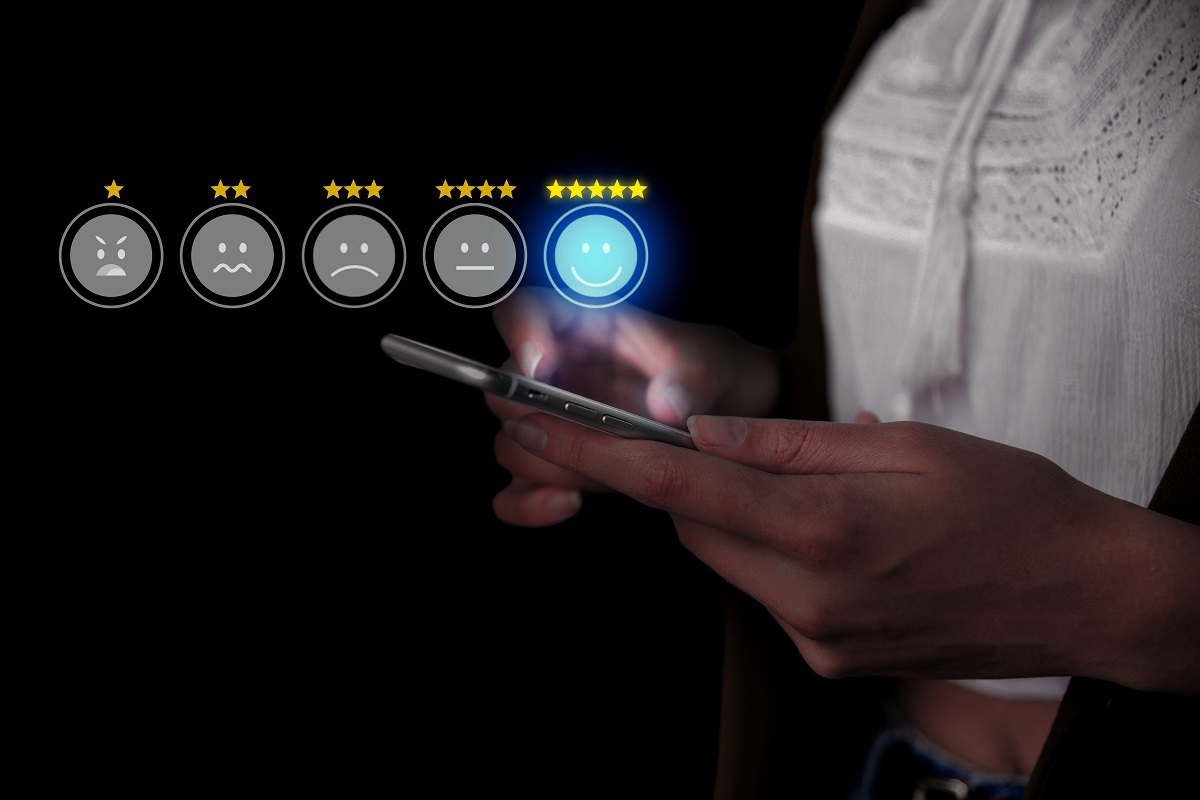 Pessoa segurando smartphone em local escuro com símbolos de emoji no ar feitos em montagem