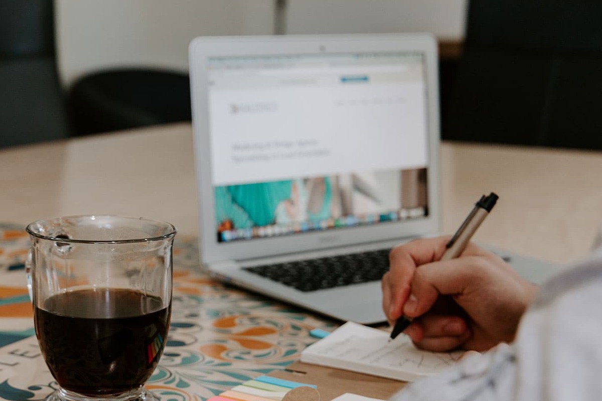 pessoa trabalhando: SEO writing pessoa trabalhando no laptop enquanto faz anotações no caderno