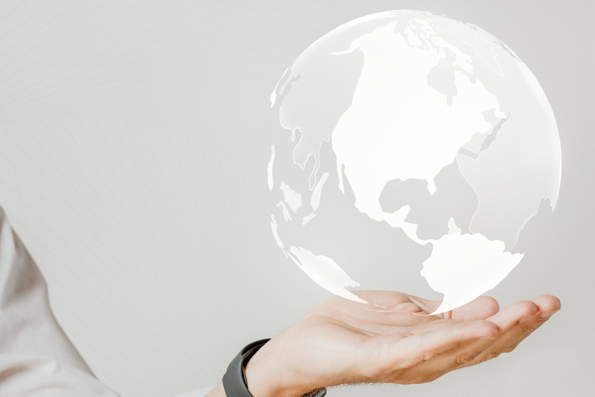 Mundo nas mãos: Saturação de palavras-chave Montagem com pessoa com seu braço erguido enquanto mostra algo no ar com a mão com palma virada para cima e um pequeno globo terrestre em branco e transparente pairando no ar sobre sua mão