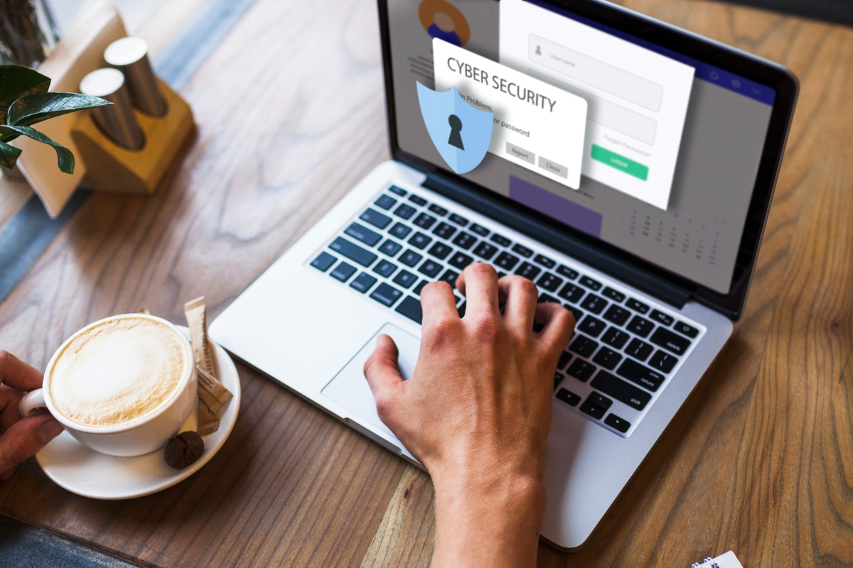 Alerta: Segurança de site Homem usando notebook sobre mesa de madeira com alerta de segurança na tela e xícara de café à sua frente