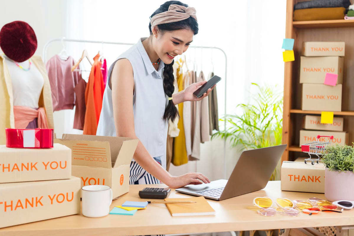 mulher trabalhando: Tipos de e-commerce mulher empreendedora, trabalhando com seu laptop e embalando encomendas