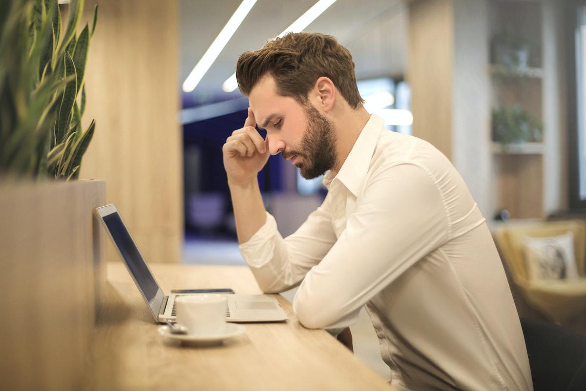 homem sentado, pensativo e usando um notebook