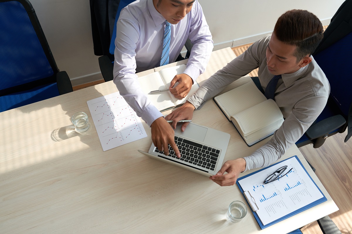 Homens conversando sobre negócios: Consultores de vendas Consultores de vendas: A imagem mostras dois homens conversando, sendo que um deles está apresentando dados sobre o negócio do outro.